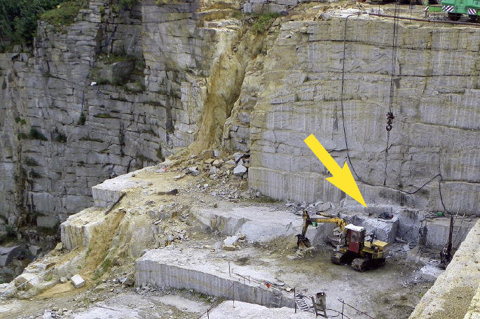 Photo of Wekom II Quarry. Andzrej's Pocket cavities are located right above the excavator as marked by the yellow arrow. A. Korzekwa photo.